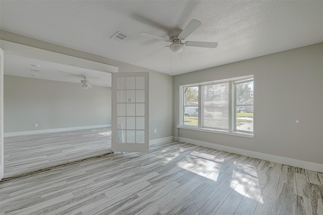 spare room with ceiling fan, light hardwood / wood-style flooring, and a textured ceiling