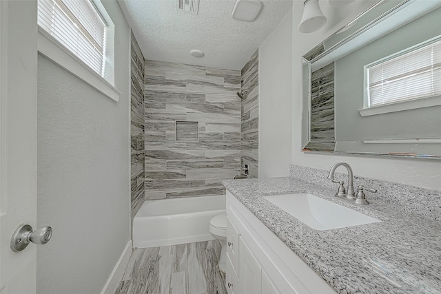 full bathroom with hardwood / wood-style floors, vanity, tiled shower / bath combo, toilet, and a textured ceiling