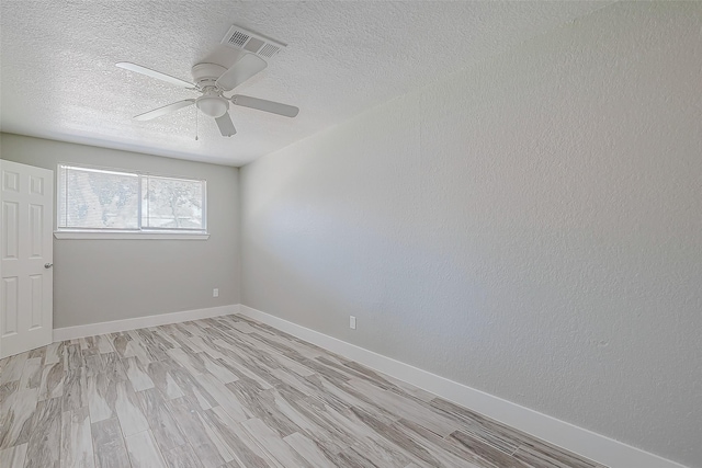 empty room featuring ceiling fan, light wood-type flooring, and a textured ceiling