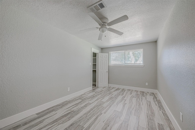 empty room featuring ceiling fan, light hardwood / wood-style floors, and a textured ceiling