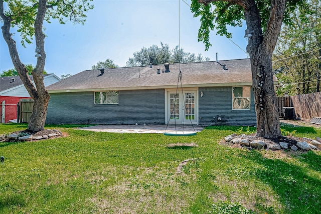 rear view of house with french doors, a patio, and a lawn