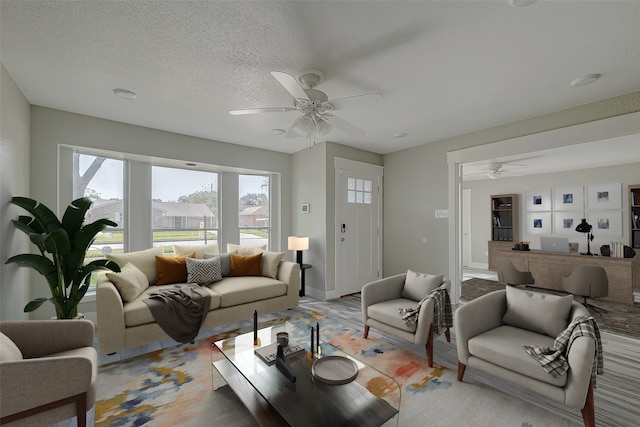 living room with ceiling fan and a textured ceiling