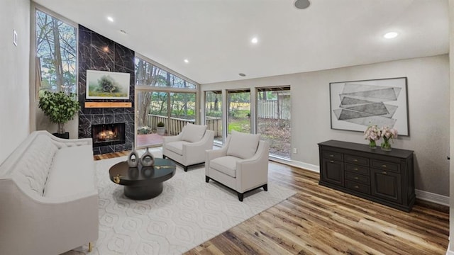 living room featuring light hardwood / wood-style floors, vaulted ceiling, and a tiled fireplace