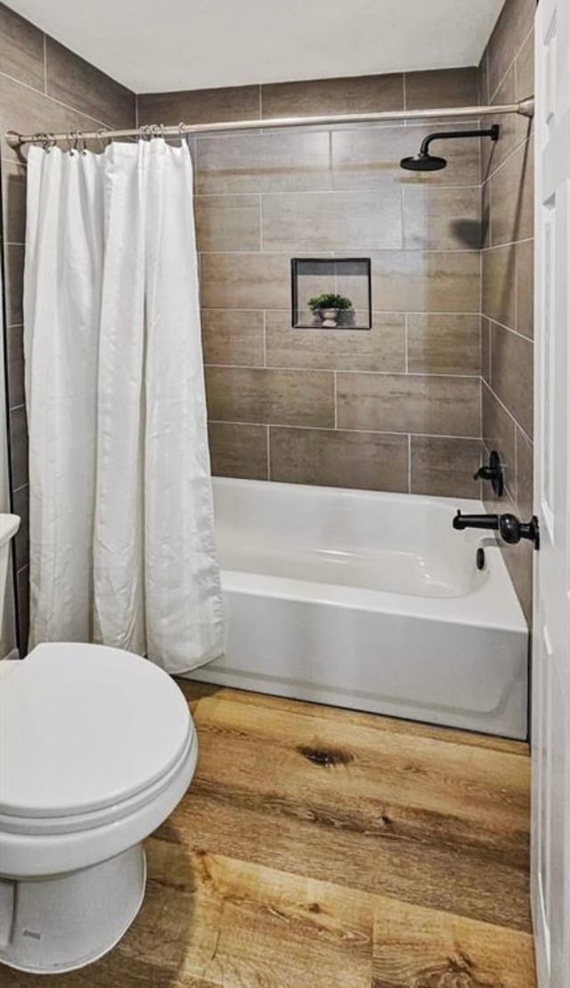 bathroom featuring shower / bath combo with shower curtain, hardwood / wood-style floors, and toilet