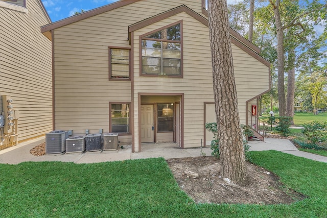 rear view of house featuring central AC unit, a patio, and a lawn