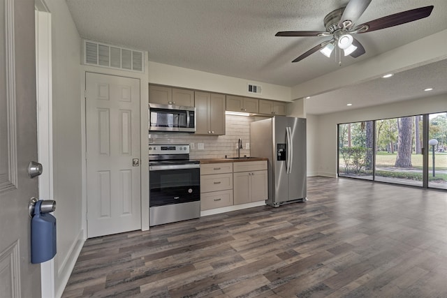 kitchen with butcher block counters, appliances with stainless steel finishes, a textured ceiling, and dark wood-type flooring