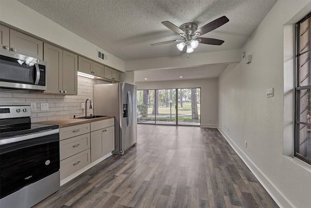 12900 Walden Rd Unit 105A, Montgomery, TX 77356 - kitchen featuring appliances with stainless steel finishes, a sink, backsplash, dark wood finished floors, and a textured ceiling