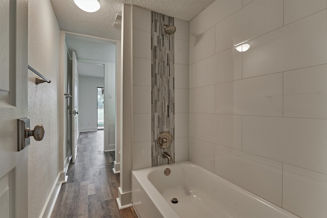 bathroom featuring hardwood / wood-style floors, a textured ceiling, and tiled shower / bath combo