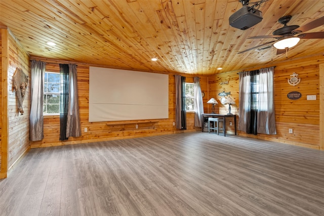 unfurnished living room featuring ceiling fan, wood-type flooring, wooden walls, and wooden ceiling