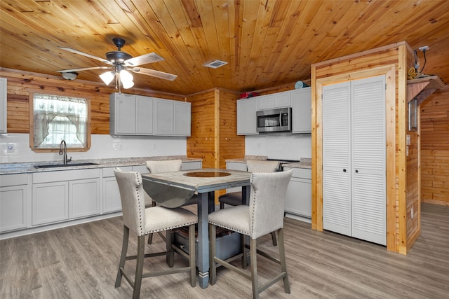 dining room with wood walls, sink, ceiling fan, light hardwood / wood-style floors, and wood ceiling