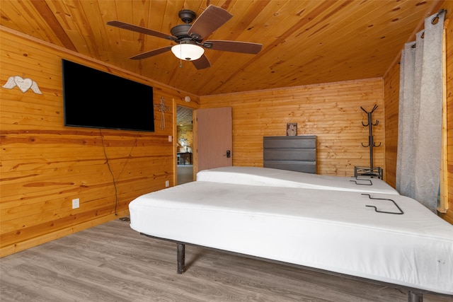 bedroom with hardwood / wood-style flooring, ceiling fan, and wood walls