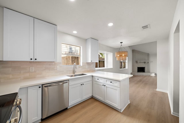 kitchen featuring light wood-type flooring, white cabinets, a fireplace, sink, and dishwasher