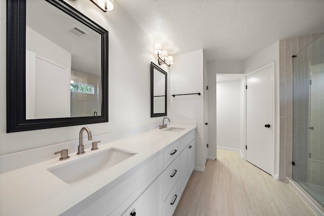 bathroom with hardwood / wood-style flooring, vanity, a shower with door, and a textured ceiling