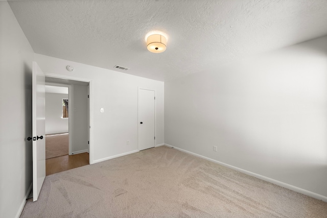 unfurnished bedroom with carpet, a textured ceiling, and a closet