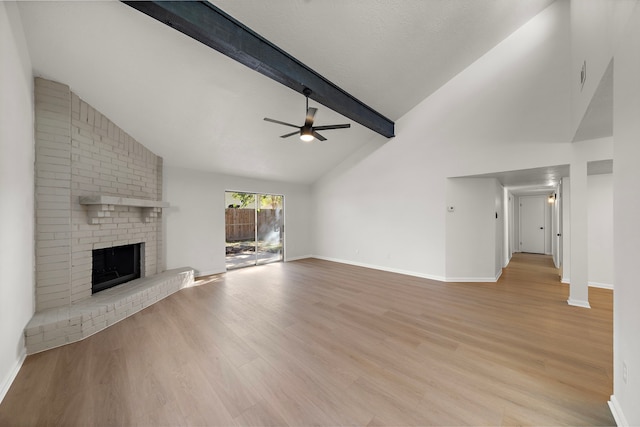 unfurnished living room with ceiling fan, beamed ceiling, high vaulted ceiling, light hardwood / wood-style floors, and a fireplace