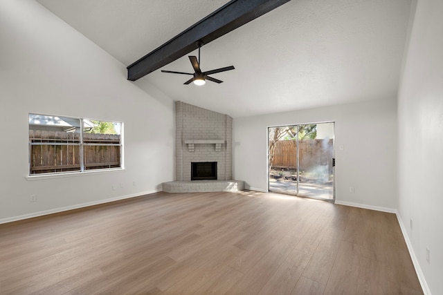 unfurnished living room with ceiling fan, a brick fireplace, light hardwood / wood-style flooring, beamed ceiling, and high vaulted ceiling