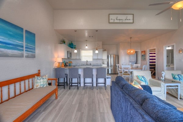 living room featuring ceiling fan with notable chandelier, light hardwood / wood-style floors, and sink