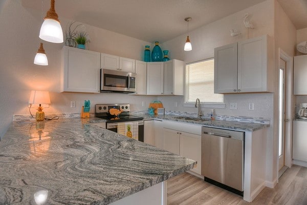 kitchen featuring hanging light fixtures, white cabinets, and stainless steel appliances