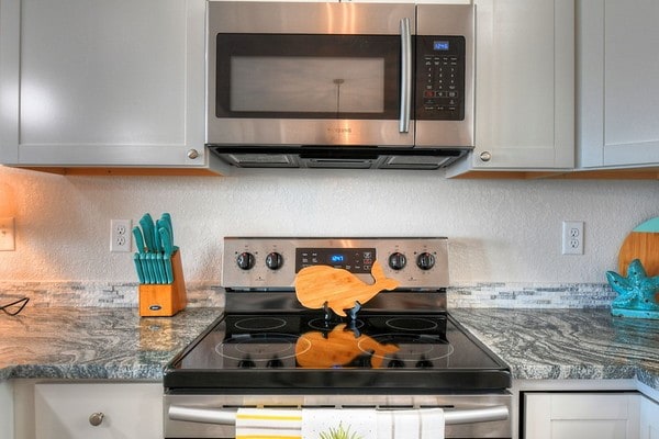 kitchen with dark stone countertops, white cabinetry, and appliances with stainless steel finishes