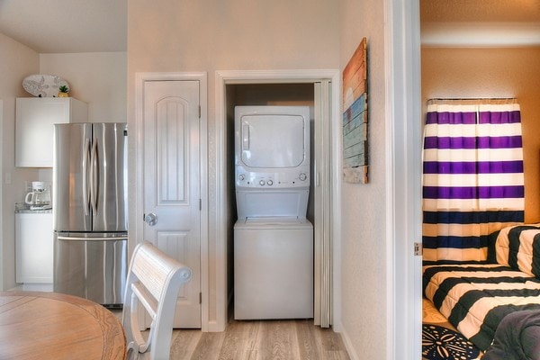 laundry area featuring stacked washing maching and dryer and light hardwood / wood-style floors