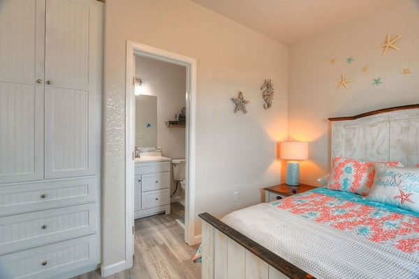 bedroom featuring connected bathroom and light hardwood / wood-style floors