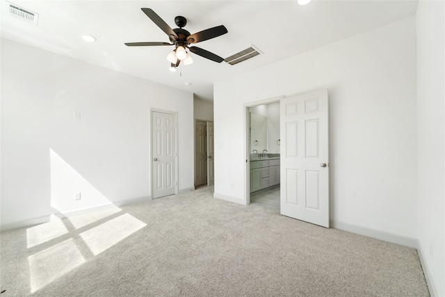 unfurnished bedroom with ensuite bathroom, sink, ceiling fan, and light carpet