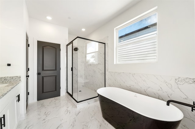 bathroom featuring plus walk in shower, vanity, and tile walls