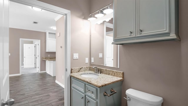 bathroom featuring hardwood / wood-style floors, vanity, toilet, and ornamental molding