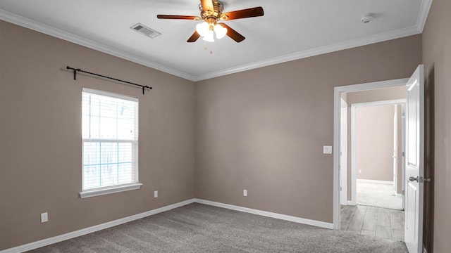 carpeted spare room with ceiling fan and ornamental molding