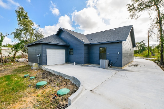 back of property with a garage and central AC