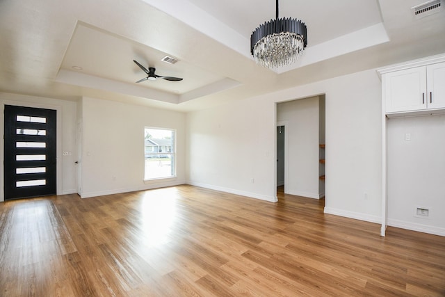 interior space featuring ceiling fan with notable chandelier, light hardwood / wood-style flooring, and a raised ceiling