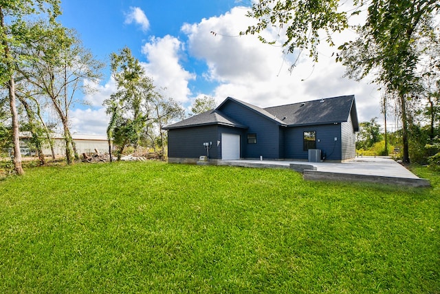 back of property featuring a lawn, cooling unit, and a garage