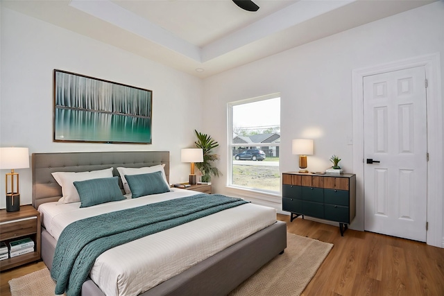 bedroom featuring hardwood / wood-style flooring and a tray ceiling