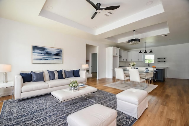 living room featuring a tray ceiling, wood-type flooring, and ceiling fan