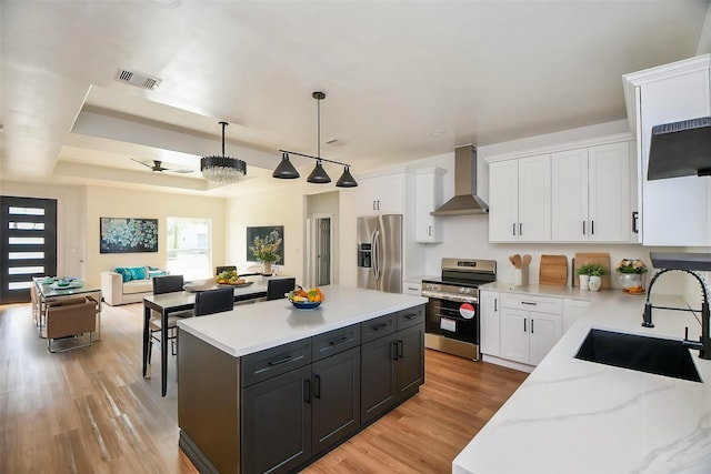 kitchen with white cabinetry, appliances with stainless steel finishes, sink, and wall chimney range hood