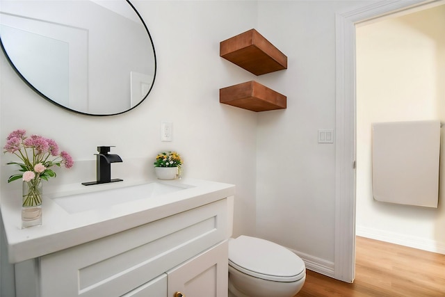 bathroom with hardwood / wood-style flooring, vanity, and toilet