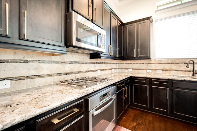 kitchen featuring sink, stainless steel appliances, tasteful backsplash, dark hardwood / wood-style floors, and dark brown cabinets