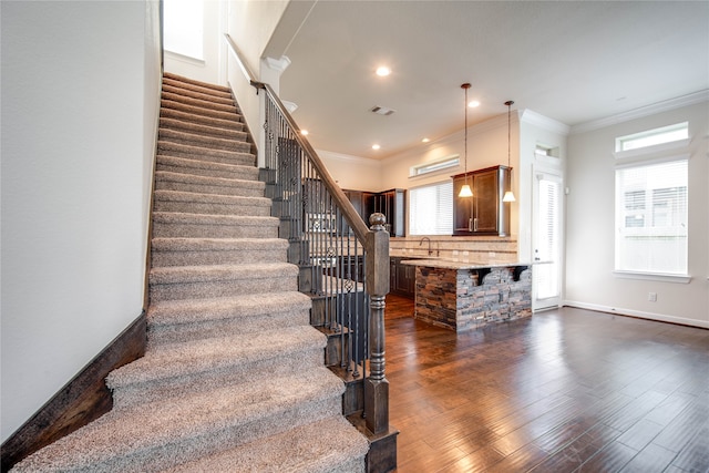 stairway with sink, wood-type flooring, and ornamental molding