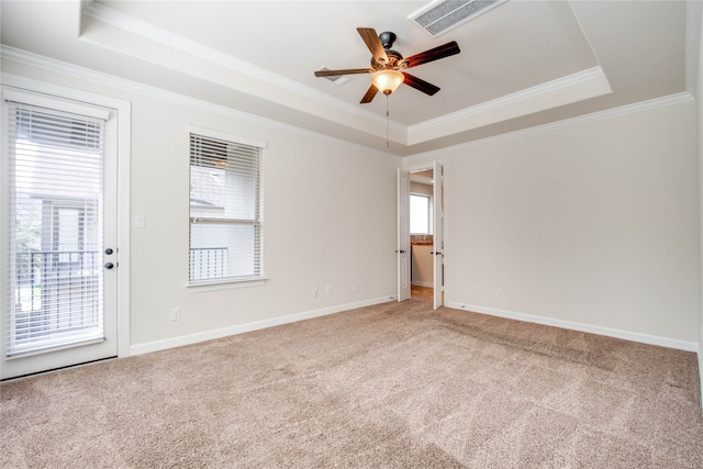 carpeted empty room with plenty of natural light, ceiling fan, a raised ceiling, and ornamental molding