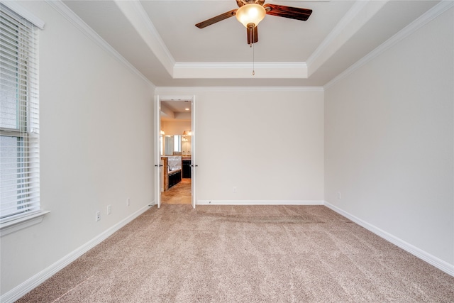 carpeted empty room featuring ceiling fan, ornamental molding, and a tray ceiling