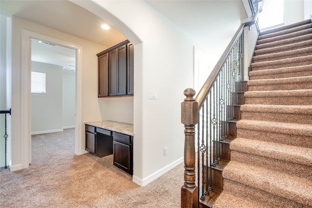 stairs with a wealth of natural light, carpet, and built in desk