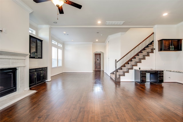 unfurnished living room featuring ceiling fan, dark wood-type flooring, and ornamental molding