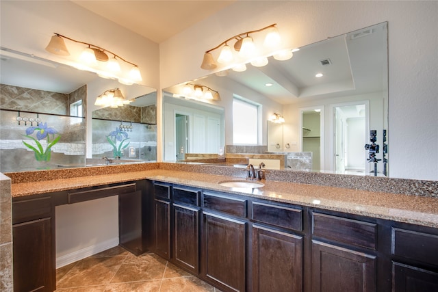 bathroom with a tray ceiling, tile patterned flooring, vanity, and tiled shower