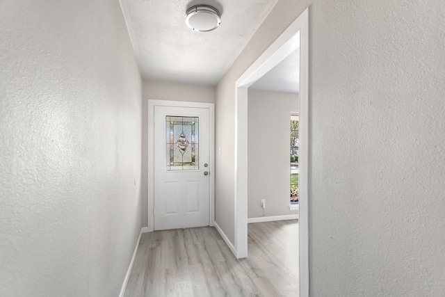 entryway with plenty of natural light, light wood-type flooring, and a textured ceiling