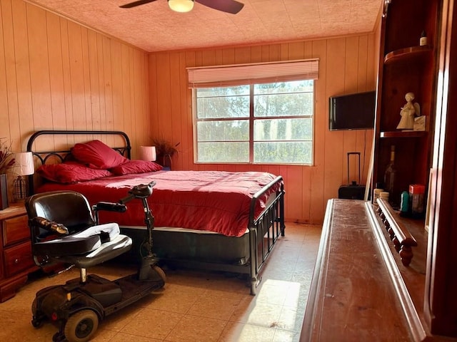 bedroom with ceiling fan and wood walls