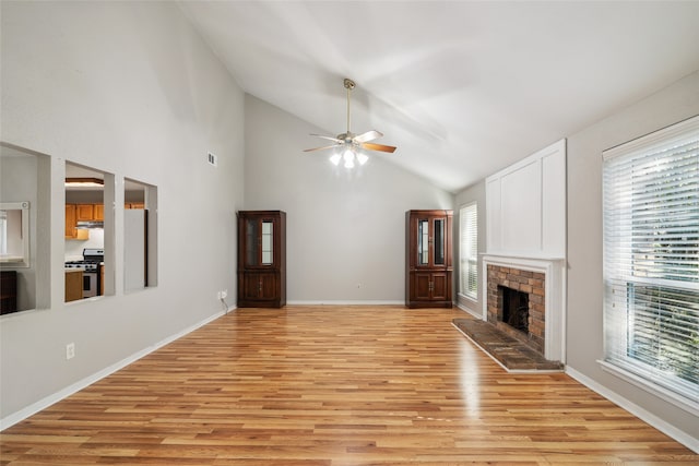 unfurnished living room featuring ceiling fan, light hardwood / wood-style floors, a fireplace, and high vaulted ceiling