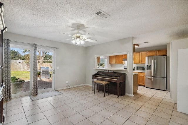 kitchen with appliances with stainless steel finishes, a textured ceiling, light tile patterned floors, and ceiling fan