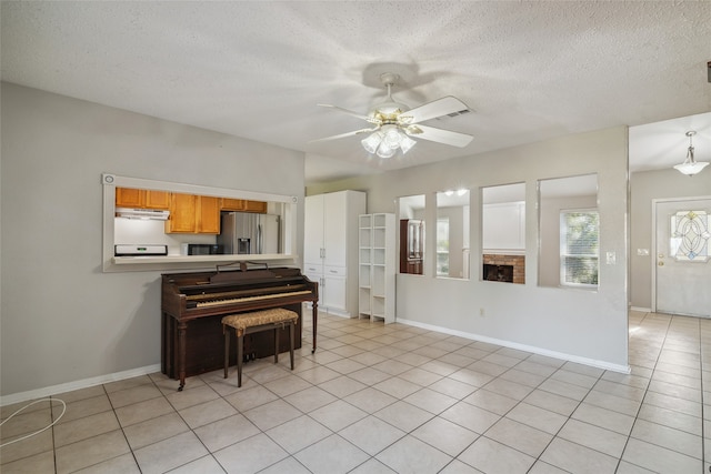 kitchen with ceiling fan, stainless steel fridge, light tile patterned flooring, and a textured ceiling