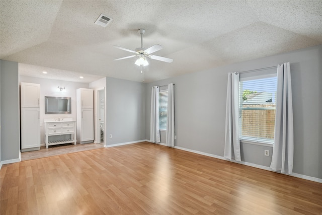 unfurnished living room with lofted ceiling, ceiling fan, light hardwood / wood-style flooring, and a textured ceiling