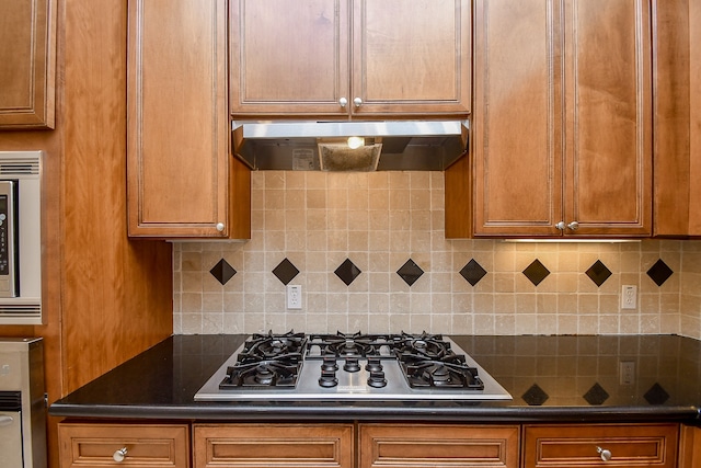 kitchen featuring decorative backsplash, appliances with stainless steel finishes, and range hood